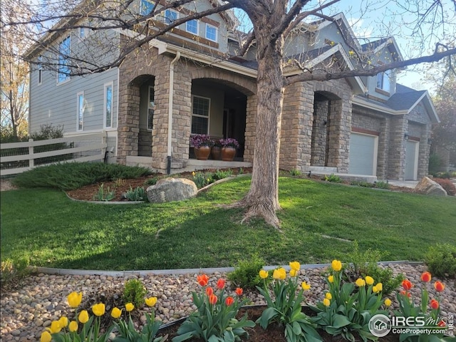 view of front of house with fence, stone siding, and a front yard