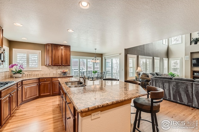 kitchen featuring a kitchen bar, light wood-type flooring, a wealth of natural light, and a sink