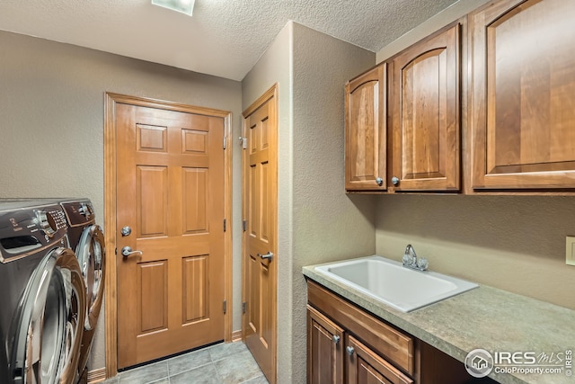 laundry area featuring a sink, a textured ceiling, independent washer and dryer, cabinet space, and a textured wall