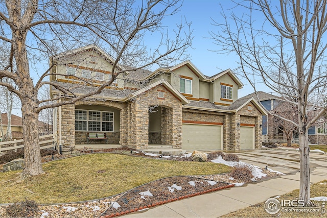 traditional-style home featuring concrete driveway, stone siding, fence, a front yard, and stucco siding