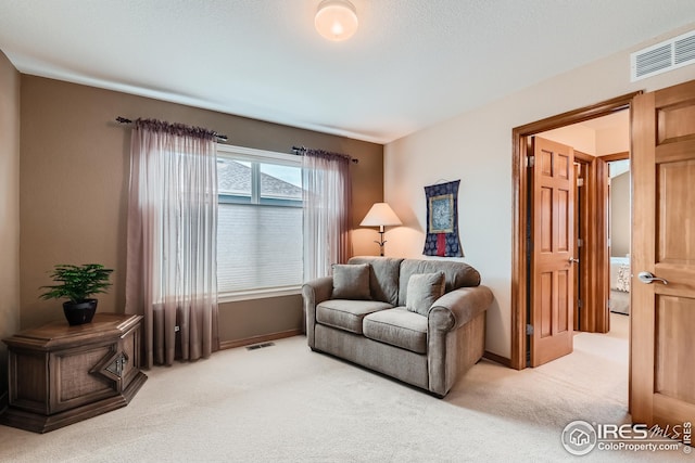 sitting room with baseboards, visible vents, and light colored carpet