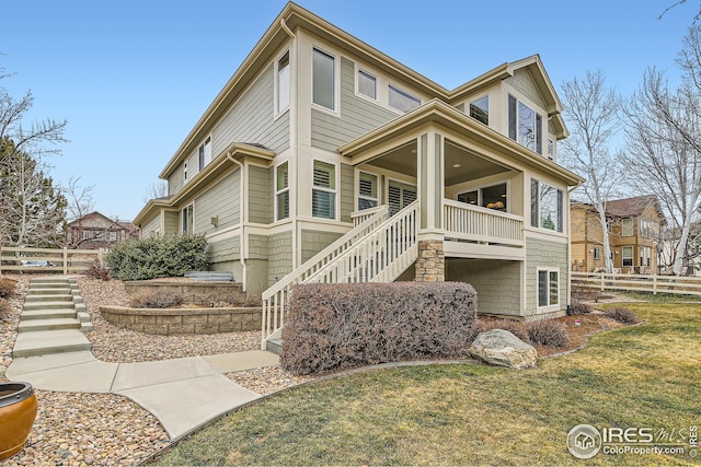 back of property featuring a lawn, fence, and stairs