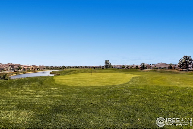 view of property's community featuring view of golf course, a yard, a residential view, and a water view
