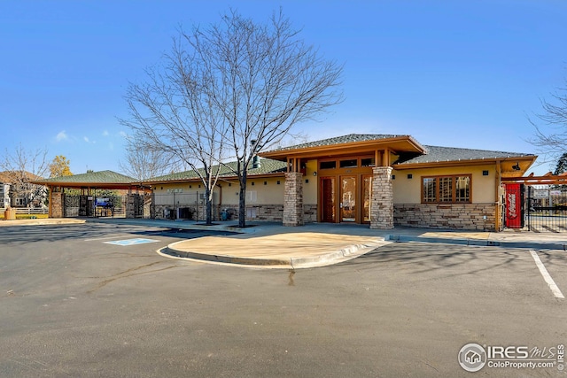 prairie-style home with stucco siding, fence, and stone siding