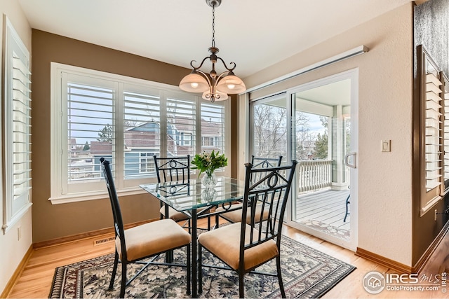 dining area with light wood-style flooring, baseboards, and an inviting chandelier