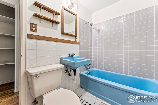 bathroom with toilet, tile walls, and bathing tub / shower combination