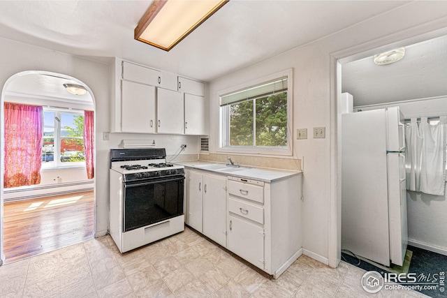 kitchen featuring a baseboard radiator, light countertops, white appliances, white cabinetry, and a sink