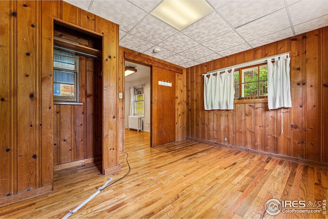 empty room featuring radiator, wood walls, and hardwood / wood-style flooring