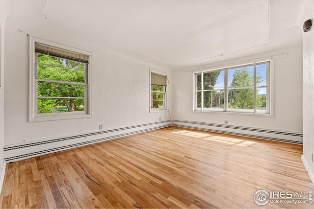 empty room with baseboard heating and hardwood / wood-style flooring