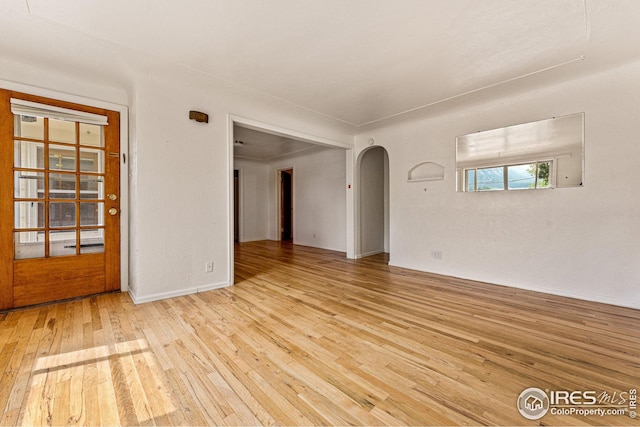 spare room with arched walkways and hardwood / wood-style flooring