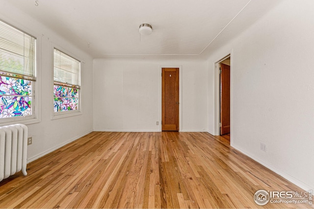 spare room with light wood-style flooring, radiator, and baseboards