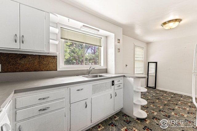 kitchen with a sink, baseboards, light countertops, white cabinetry, and open shelves