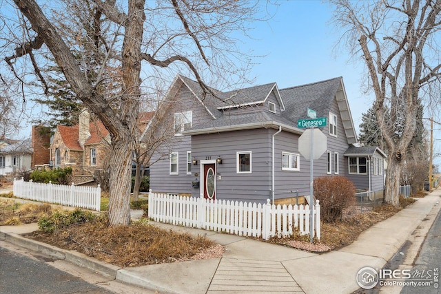 view of front of home with a fenced front yard and roof with shingles