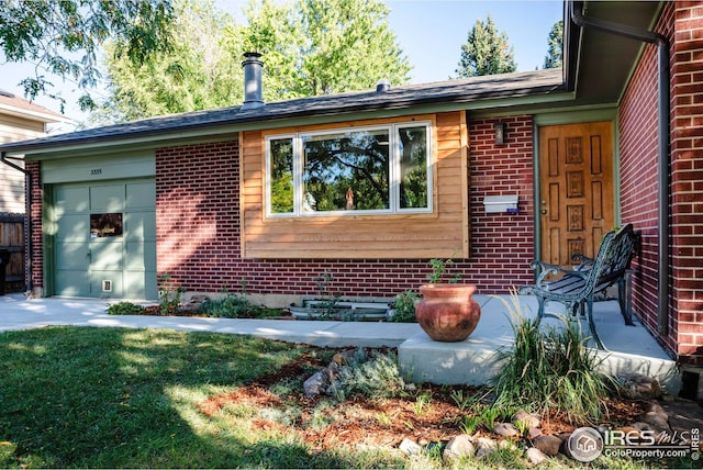 doorway to property featuring a garage and brick siding