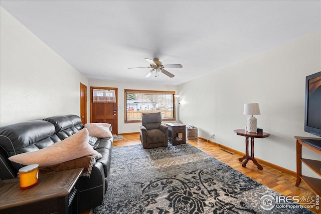 living room featuring baseboards, light wood-type flooring, and ceiling fan