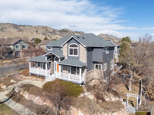 view of front of property with covered porch, a mountain view, and a shingled roof