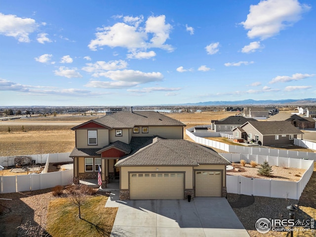 traditional home featuring driveway, a residential view, roof with shingles, an attached garage, and fence private yard