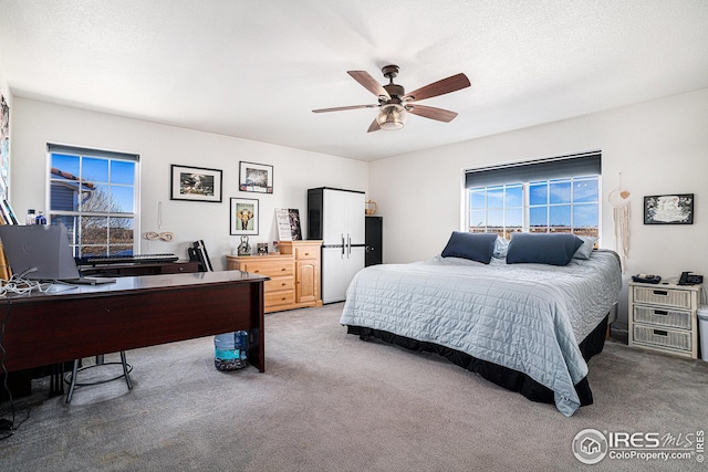 carpeted bedroom featuring a ceiling fan and a textured ceiling