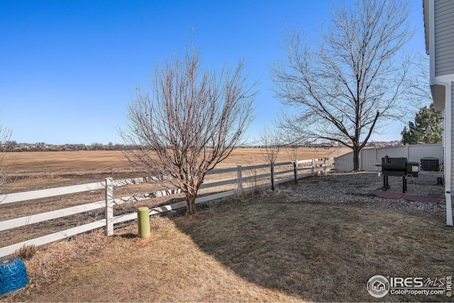 view of yard featuring a rural view, a patio, and a fenced backyard