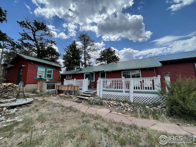 view of front of house featuring a wooden deck, log veneer siding, and metal roof