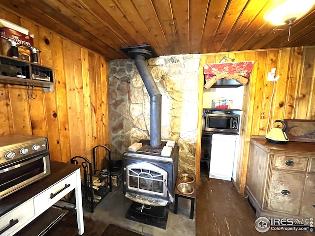 kitchen with wood ceiling, stainless steel microwave, a wood stove, wood walls, and fridge