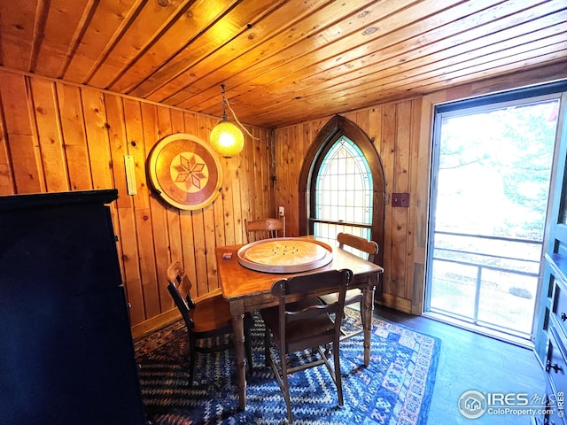 dining space featuring wood walls, wood finished floors, baseboards, and wood ceiling