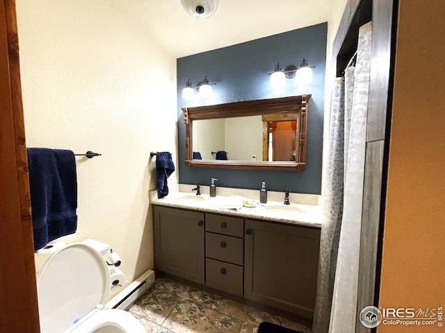 bathroom featuring baseboard heating, toilet, double vanity, and a sink