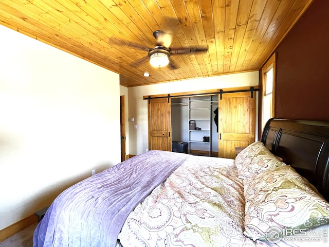 carpeted bedroom featuring crown molding, baseboards, ceiling fan, wood ceiling, and a barn door