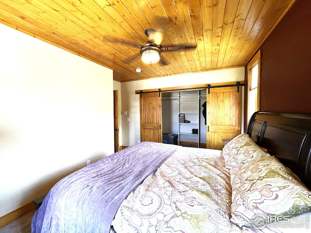 carpeted bedroom with a barn door, ceiling fan, and wood ceiling