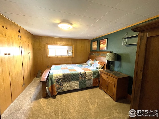 bedroom featuring wooden walls and light colored carpet