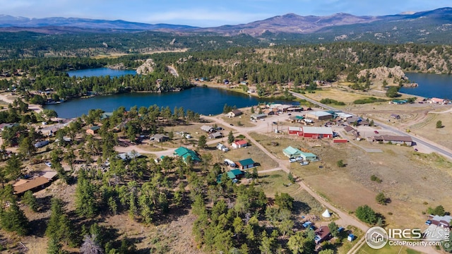 aerial view featuring a forest view and a water and mountain view