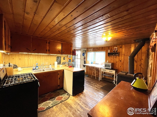 kitchen with a sink, wooden walls, a peninsula, wood ceiling, and hardwood / wood-style floors