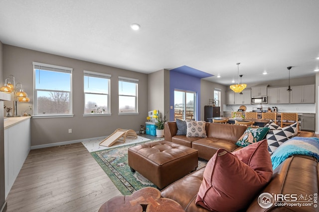 living area featuring an inviting chandelier, recessed lighting, baseboards, and light wood finished floors