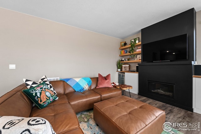 living room featuring a glass covered fireplace and wood finished floors