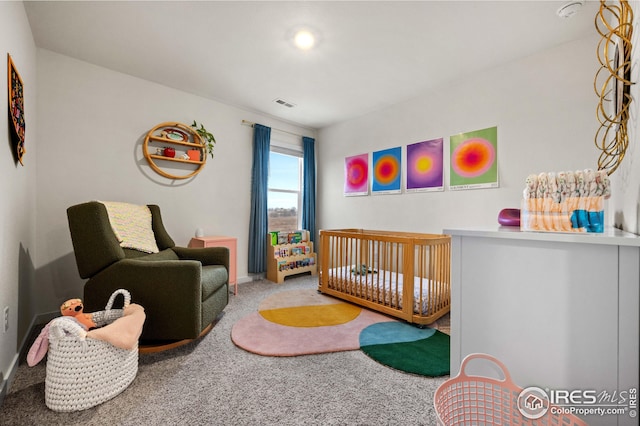 bedroom with visible vents, a crib, and carpet flooring