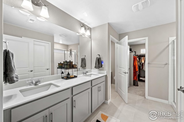 bathroom with double vanity, a stall shower, visible vents, and a sink