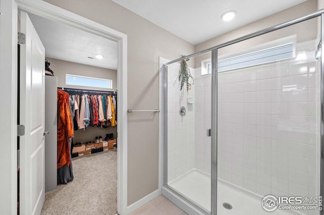 bathroom with recessed lighting, a walk in closet, baseboards, and a stall shower