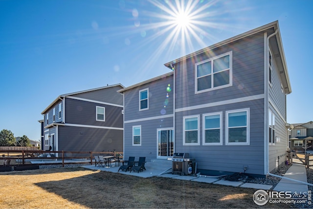 rear view of property with a yard, a patio, and fence