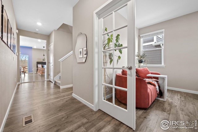 hall featuring wood finished floors, visible vents, baseboards, recessed lighting, and stairs