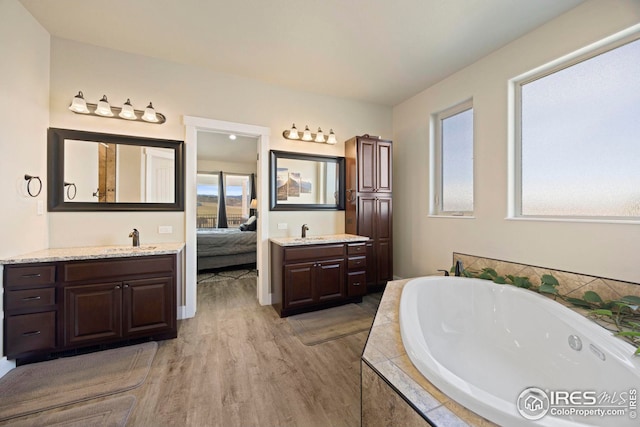 ensuite bathroom with a sink, two vanities, a bath, and ensuite bathroom