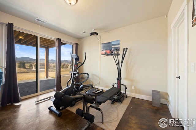 exercise area featuring visible vents, a mountain view, and baseboards