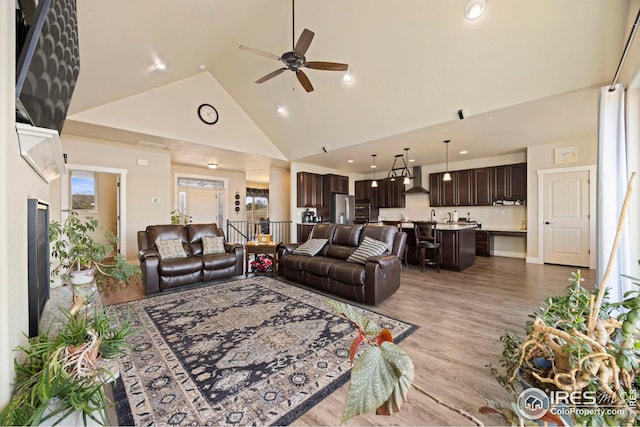 living area with recessed lighting, a ceiling fan, light wood-style floors, and high vaulted ceiling