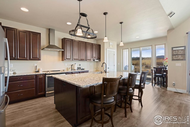 kitchen featuring a sink, wall chimney exhaust hood, wood finished floors, and stainless steel range with electric cooktop