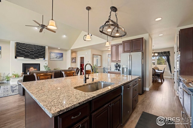 kitchen featuring a glass covered fireplace, a sink, stainless steel dishwasher, refrigerator with ice dispenser, and open floor plan