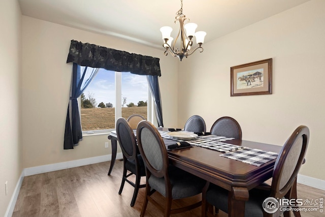 dining room with baseboards, light wood-type flooring, and a chandelier