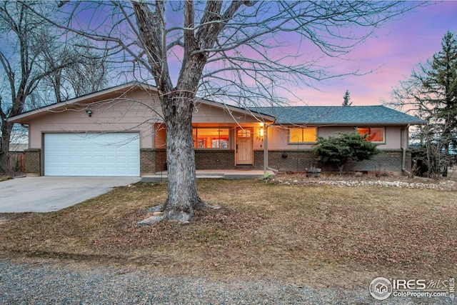 ranch-style house featuring concrete driveway, an attached garage, covered porch, and brick siding