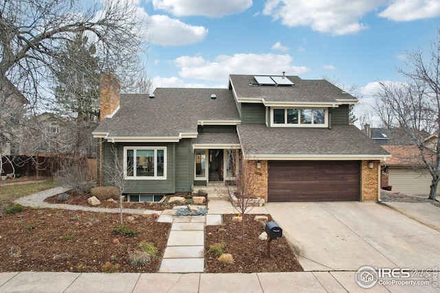 view of front facade featuring driveway, roof with shingles, solar panels, an attached garage, and a chimney