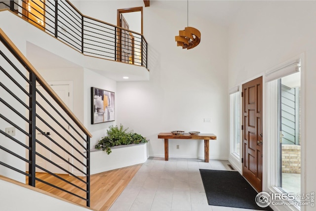 foyer entrance with stairway, a high ceiling, baseboards, and wood finished floors