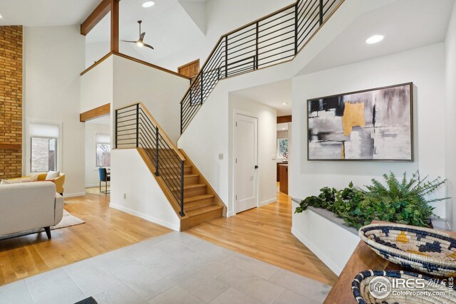 interior space featuring wood finished floors, baseboards, a high ceiling, stairs, and beamed ceiling