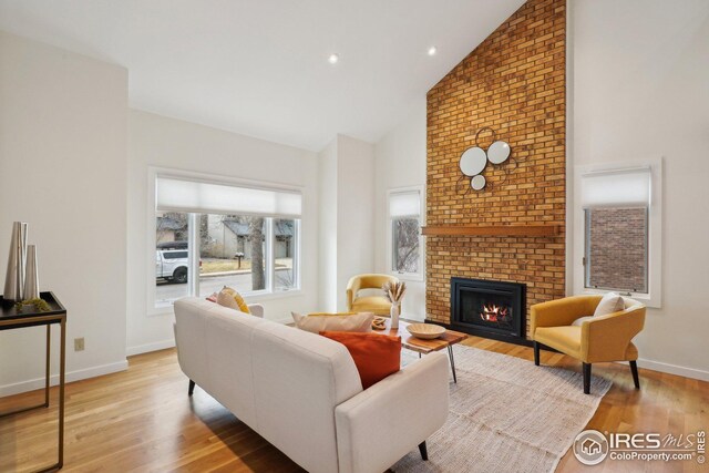 living room with high vaulted ceiling, recessed lighting, light wood-style floors, baseboards, and a brick fireplace